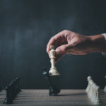 Hand,of,businessman,wearing,suit,moving,chess,figure,in,competition