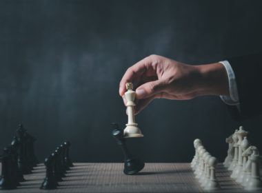 Hand,of,businessman,wearing,suit,moving,chess,figure,in,competition
