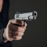 Male,hand,holding,a,gun,on,black,background, ,a