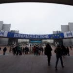 People,walk,toward,a,banner,advertising,the,european,elections,outside