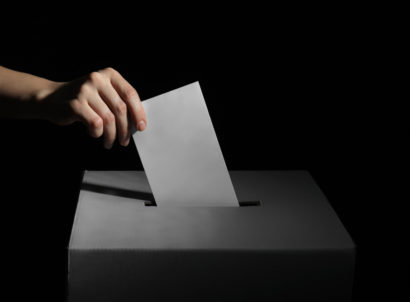 Voting,woman,near,ballot,box,on,dark,background