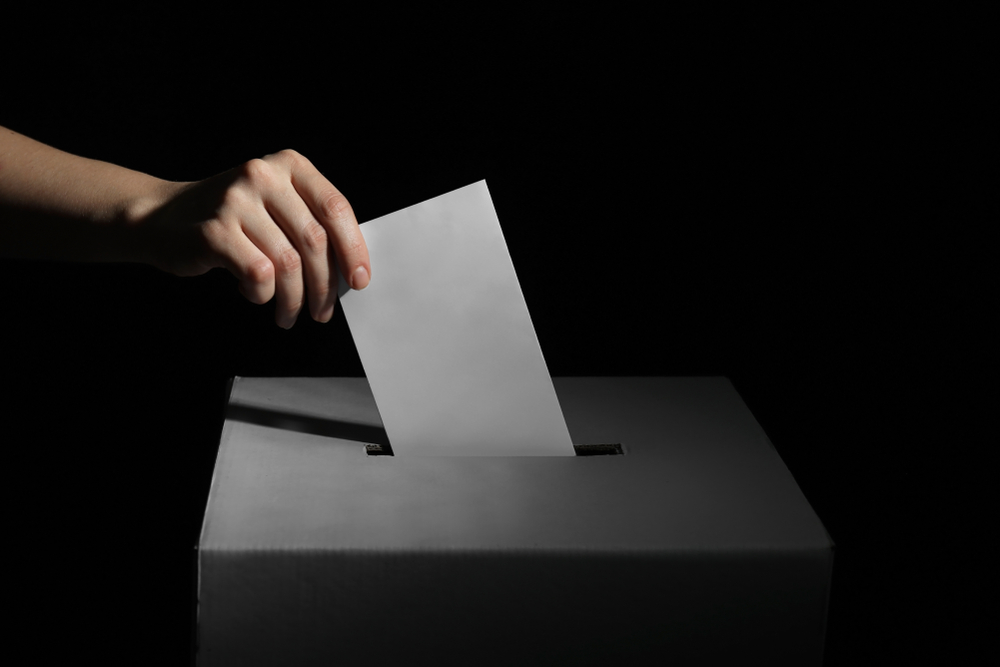 Voting,woman,near,ballot,box,on,dark,background