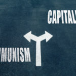 Communism,vs,capitalism,choice,concept,,two,direction,arrows,on,asphalt