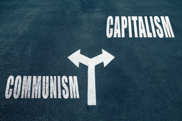 Communism,vs,capitalism,choice,concept,,two,direction,arrows,on,asphalt