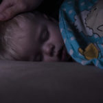 Little,baby,boy,sweetly,sleeps,in,bed,,dad,puts,his