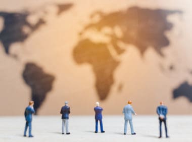 Miniature,people,:businessman,standing,on,world,map,background,,,growing