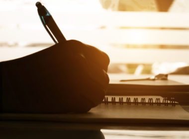 Close,up,hand,writing,notes,on,notbook,on,desk,in