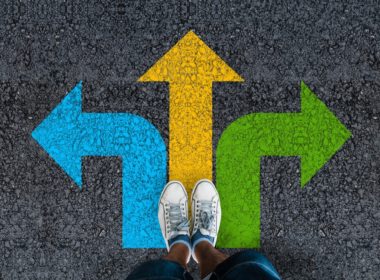 Man,legs,in,sneakers,standing,on,road,with,three,direction