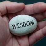 Wisdom,text,engraved,on,zen,stones,with,hand,background ,wisdom