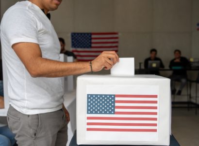 Hispanic,man,placing,his,vote,ballot,in,the,polling,box