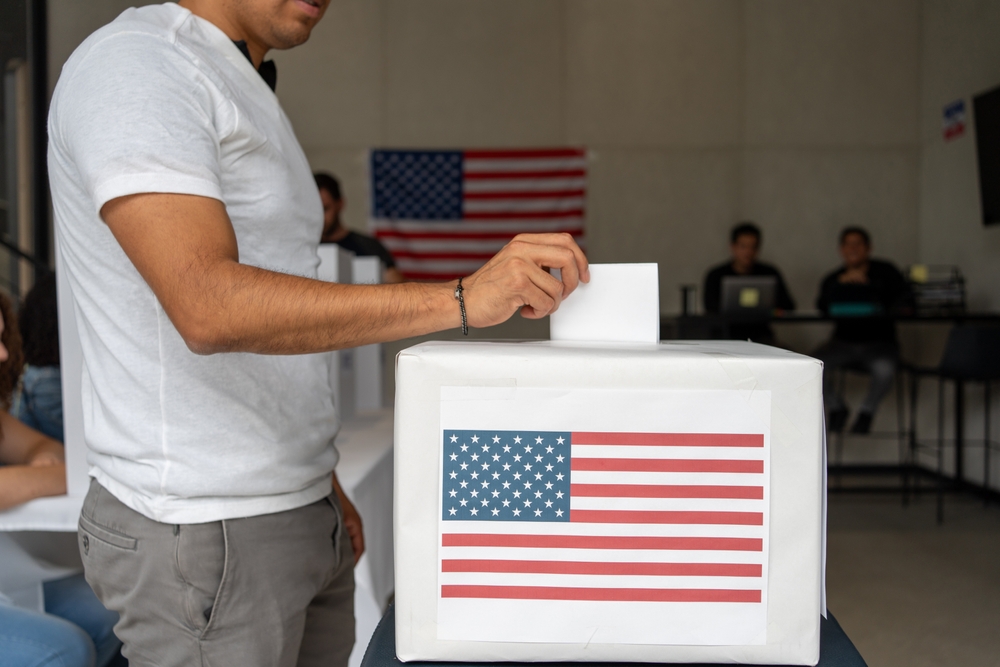 Hispanic,man,placing,his,vote,ballot,in,the,polling,box