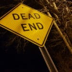 Angled,dead,end,sign,at,night,with,creepy,trees,and