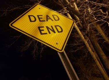Angled,dead,end,sign,at,night,with,creepy,trees,and