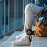 Man,with,backpack,and,face,mask,sitting,on,stairs,at