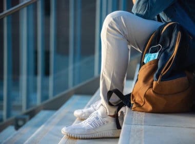 Man,with,backpack,and,face,mask,sitting,on,stairs,at