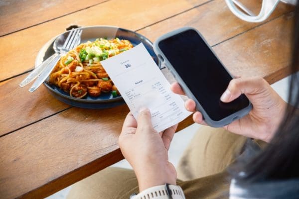 Closeup,woman,is,holding,a,food,receipt,and,smart,phone