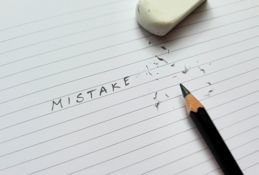 Close,up,of,pencil,eraser,correcting,word,mistakes,on,white