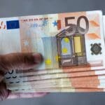 A,man,holds,a,stack,of,50,euro,banknotes,in