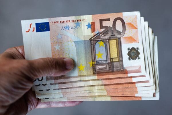 A,man,holds,a,stack,of,50,euro,banknotes,in