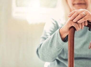 Relax,,cane,and,hands,of,elderly,woman,on,sofa,with