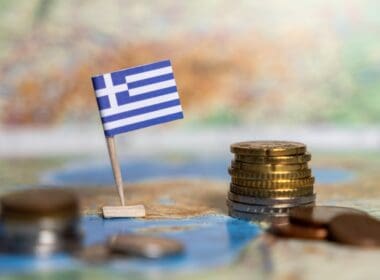 Greek,flag,with,coins,on,a,map,representing,the,economy,