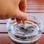 Hand,putting,out,cigarette,in,ashtray ,glass,ashtray,with,cigarette