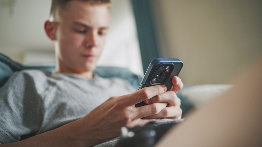 Caucasian,teenager,chats,in,messaging,app,with,friends,or,watches