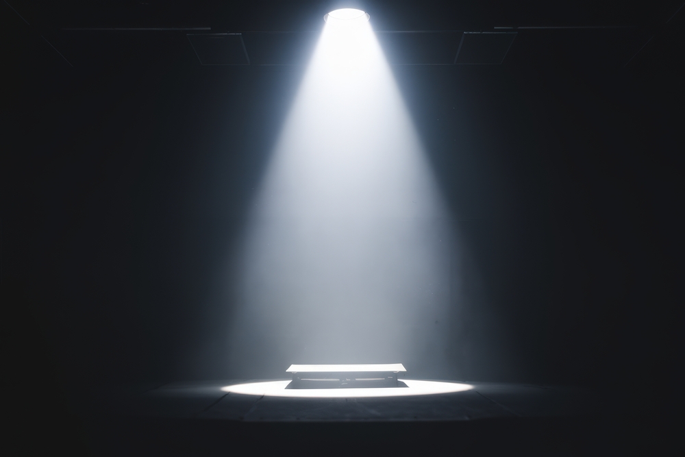 A,single,spotlight,illuminates,an,empty,table,on,a,dark