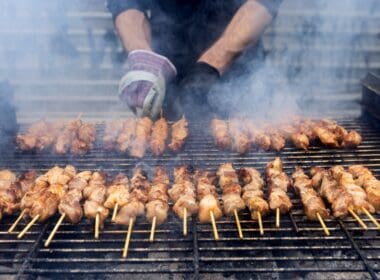 A,grill,filled,with,skewers,of,meat,cooking,over,open