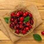 Fresh,cherries,in,bowl,on,wooden,background,,top,view
