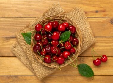 Fresh,cherries,in,bowl,on,wooden,background,,top,view