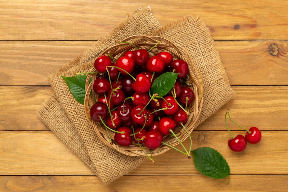 Fresh,cherries,in,bowl,on,wooden,background,,top,view