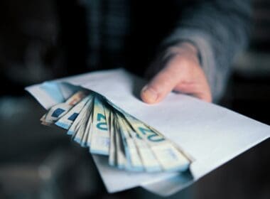 Man,hand,giving,an,envelope,full,of,euros,banknotes