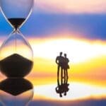 Silhouettes,of,people,stand,before,a,giant,hourglass,at,sunset,