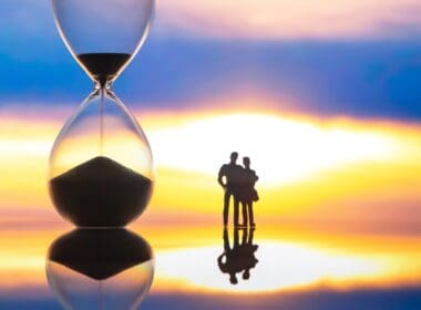 Silhouettes,of,people,stand,before,a,giant,hourglass,at,sunset,