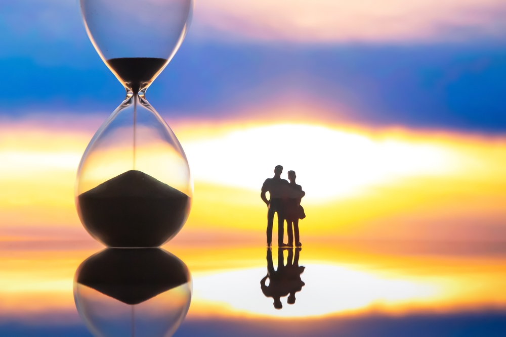 Silhouettes,of,people,stand,before,a,giant,hourglass,at,sunset,