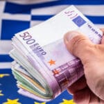 Euro,banknotes,in,man,hand,flags,greece,and,european,union
