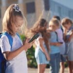 Pupils,stand,in,the,schoolyard,and,look,at,phones ,business