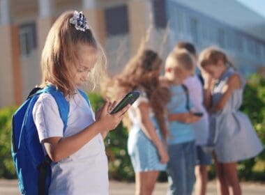 Pupils,stand,in,the,schoolyard,and,look,at,phones ,business
