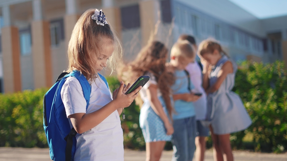 Pupils,stand,in,the,schoolyard,and,look,at,phones ,business