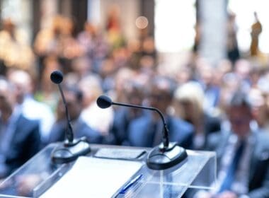 Microphones,in,focus,,unrecognizable,people,in,background,at,business,conference,