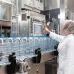 Female,worker,in,factory,checking,robotic,line,for,water,bottling
