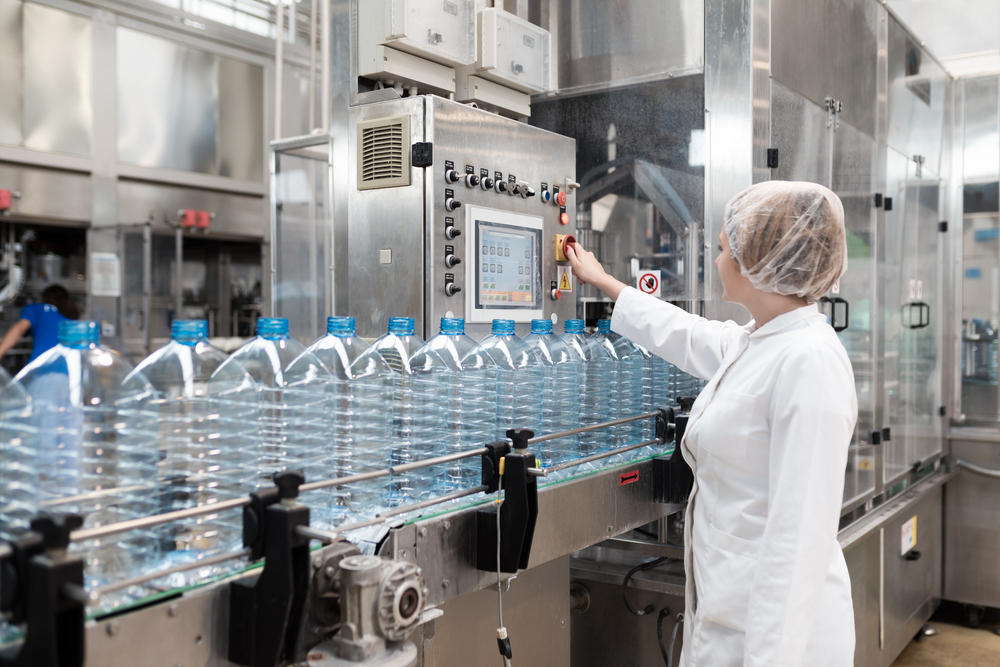 Female,worker,in,factory,checking,robotic,line,for,water,bottling