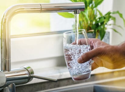 Hand,holding,a,glass,of,water,poured,from,the,kitchen