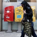 A,woman,walks,in,front,of,post,office,in,thessaloniki,