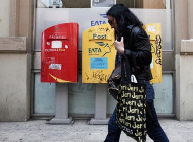 A,woman,walks,in,front,of,post,office,in,thessaloniki,