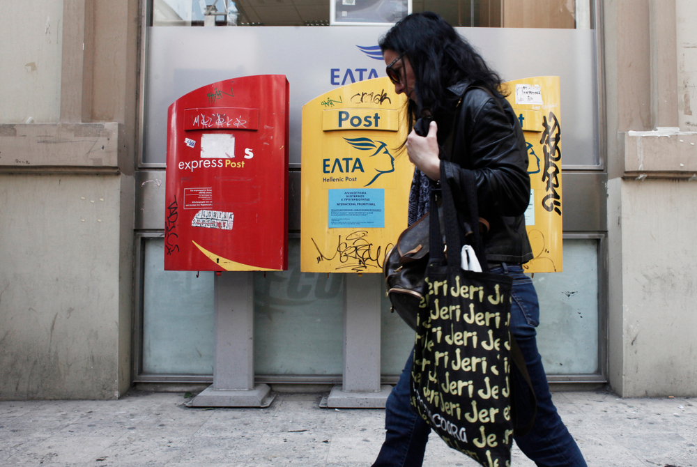A,woman,walks,in,front,of,post,office,in,thessaloniki,