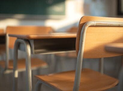 Sunlit,wooden,school,desks,and,chairs,in,an,empty,classroom,