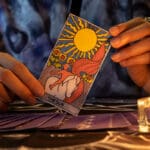 Fortune,teller,of,hands,holding,the,sun,card,and,tarot