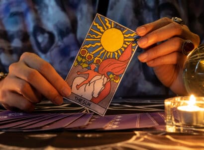 Fortune,teller,of,hands,holding,the,sun,card,and,tarot